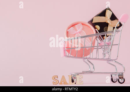 Online shopping concept, shopping cart with gift boxes in pink background with copy space. Stock Photo