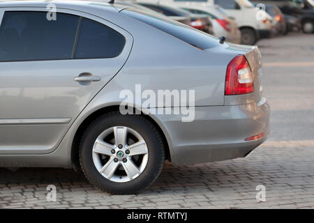 Kyiv, UKRAINE- February 27, 2019: Side view of silver car parked in paved parking lot area on blurred suburb road background on bright sunny day. Tran Stock Photo