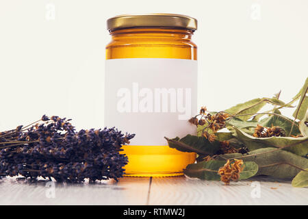 Honey in jar with lavender and linden flowers on vintage wooden background. Stock Photo