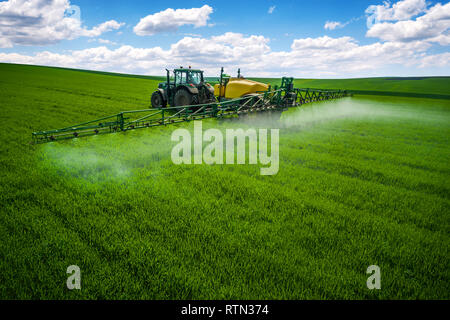 Aerial view of farming tractor plowing and spraying on field. Stock Photo