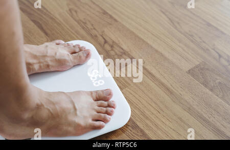 Close up a man feet on body scale checking body weight, dieting and lose weight concept Stock Photo