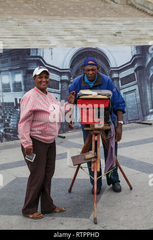 Havana, Cuba - 18 January 2013: A view of the streets of the city with cuban people. An old man  photographing with an antique camera. Stock Photo