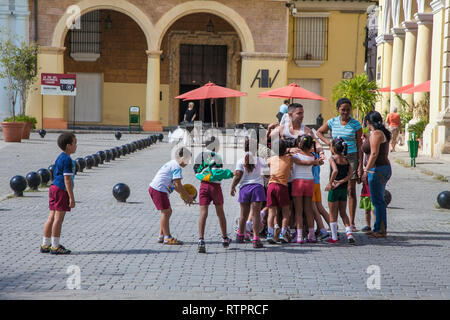 Havana, Cuba - 22 January 2013: A view of the streets of the city with cuban people. Many children are flocking to their educator. Stock Photo