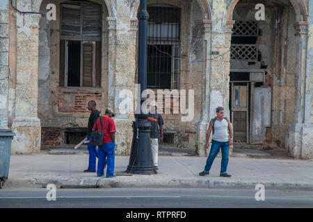 Havana, Cuba - 22 January 2013: A view of the streets of the city with cuban people. Four men are waiting for the bus. Stock Photo
