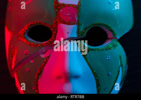 White mask on the dark wall in red light Stock Photo