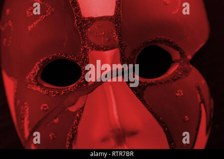 White mask on the dark wall in red light Stock Photo