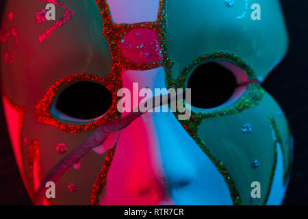 White mask on the dark wall in red light Stock Photo