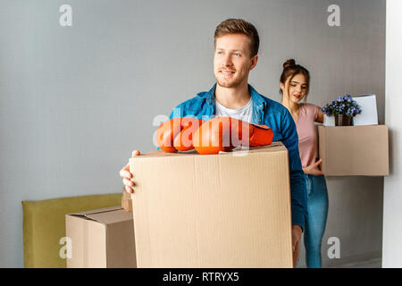 Young family couple bought or rented their first small apartment. Cheerful man and woman carry boxes with stuff. Smile and excited Stock Photo