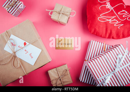 Buying presents for Valentines day with a gold card. Gift boxes and heart pillow on pink background Stock Photo
