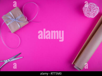 Valentines day gift wrapping with boxes and scissors on pink background. Stock Photo