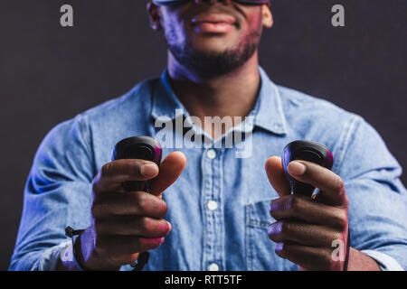Handheld controllers for video games in hands of african unrecognizable man, close up, focus on hands. Stock Photo