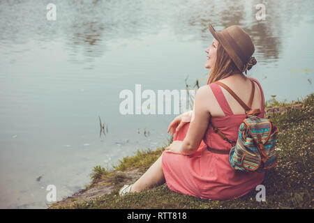 Teenager traveler girl sits beside the river before rain Stock Photo