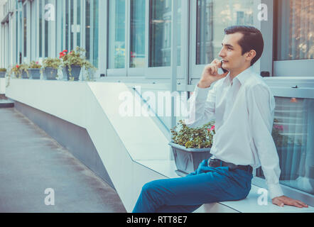 Young buisnessman talking on the phone sitting by business center Stock Photo