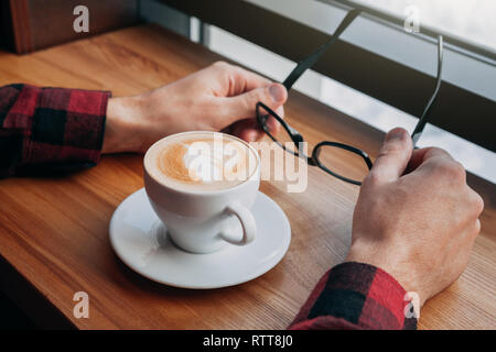 Young hipster enjoys coffee in the cafe in front of the window Stock Photo