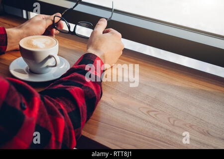Young handsome man enjoys coffee in the cafe in front of the window Stock Photo