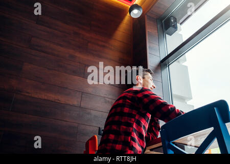 Young handsome man enjoys coffee in the cafe in front of the window Stock Photo