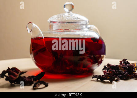 Red hibiscus tea in glass transparent teapot at wooden table Stock Photo