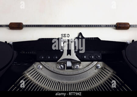 Old retro vintage black typewriter with close-up typing text SEO as heading on aged paper