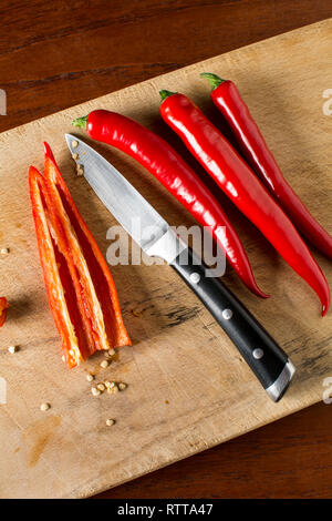 Deseeding Red hot chilli peppers on a carving board with knife Stock Photo