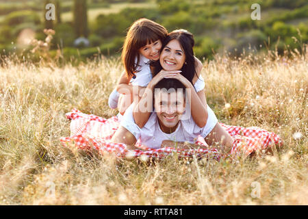 Family smiling lying on the grass on the nature. Stock Photo