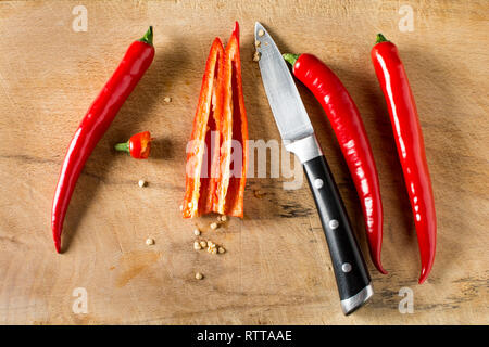 Deseeding Red hot chilli peppers on a carving board with knife Stock Photo