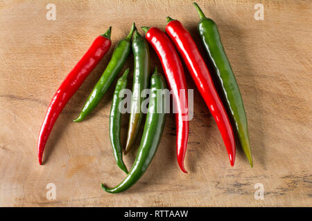 Red and green hot chilli peppers on a carving board with knife Stock Photo