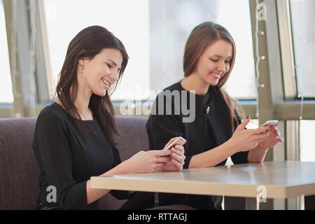 employees using their smartphones sitting at a table in a cafe Stock Photo