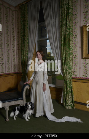 Princess Victoria stands in a grand room to re create an historic painting by George Hayter- Her Spaniel dash is at her feet Stock Photo