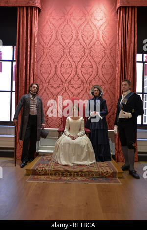 Queen Victoria sits on a throne at Kensington palace- the room is red and she wears a white dress, she is surrounded by 2 gentlemen & Baroness Lehzen Stock Photo