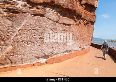 Modern rock carvings graffiti in the red sandstone on the undercliff walk at Sidmouth on the Jurassic Coast, Devon, England, UK Stock Photo