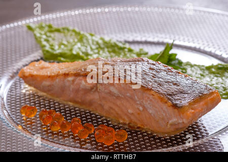 Salmon with roasted skin and orange caviar in back lit Stock Photo