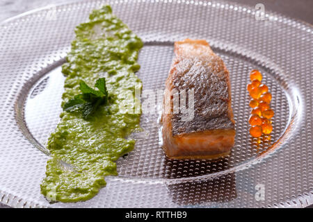 Roasted salmon fish with skin and mushy peas and caviar in backlight Stock Photo