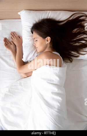 Vertical, beautiful young woman sleeping in comfortable bed Stock Photo
