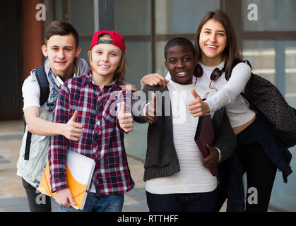 Four friends with folders and backpacks near college Stock Photo