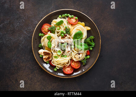 Pasta Chicken Primavera. Spaghetti pasta with grilled chicken meat, vegetables and basil, top view, copy space. Seasonal pasta primavera recipe. Stock Photo