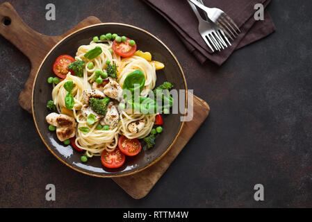 Pasta Chicken Primavera. Spaghetti pasta with grilled chicken meat, vegetables and basil, top view, copy space. Seasonal pasta primavera recipe. Stock Photo