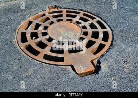 Cast-iron manhole cover storm sewer in the park close-up Stock Photo