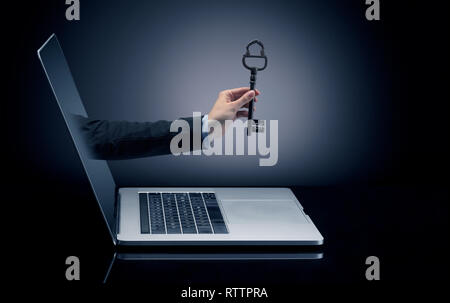 Hand with huge vintage key coming out of a laptop with sparkling effects  Stock Photo