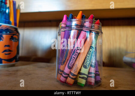 Retro clear glass jar containing coloured pencils and coloured Crayons Stock Photo