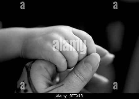 Mother holding her daughters hand, tattoo on mothers hand Stock Photo