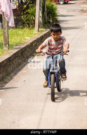 young Malaysian boy riding bicycle in Kuala Lumpur street