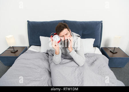 Again unhappy in morning. Tips for waking up early. Man bearded hipster sleepy face waking up. Daily schedule for healthy lifestyle. Alarm clock ringing. Problem early morning awakening. Get up early. Stock Photo