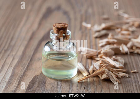 A bottle of essential oil with pieces of cedar wood on a table Stock Photo