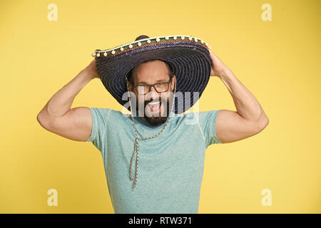 Mexican party. Man on smiling face in sombrero hat celebrating, yellow background. Guy with beard looks festive in sombrero. Fest and holiday concept. Man in festive mood at party celebrating. Stock Photo