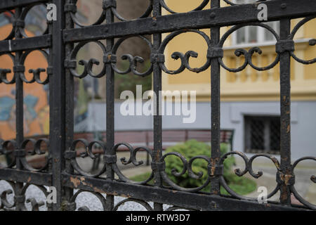 An old iron cast fence with floor circles and cracked fights. Old vintage retro black painted iron fence ornaments close up Stock Photo