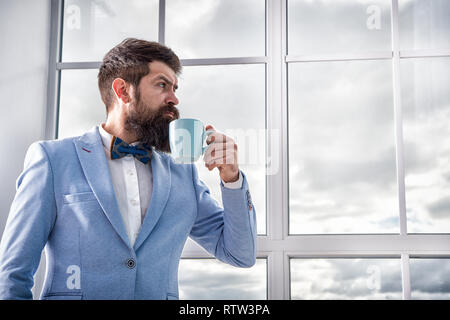 good morning coffee. serious bearded man drink coffee. businessman in formal outfit. modern life. business man at window. future success. morning inspiration. copy space. enjoying morning coffee. Stock Photo