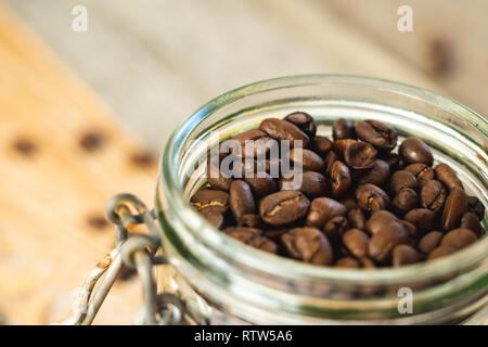 Top view of a glass jar filled with coffee beans on rustic wooden boards