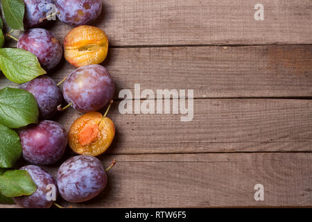 frame of plums on the old wooden background Stock Photo