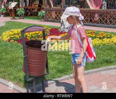 Girl throws trash into an urn in the park Stock Photo