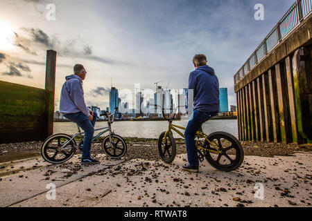 Isle of Dogs, London, UK. 2nd March 2019. Vintage View. Two middle aged men sat on their vintage BMX Bikes enjoy the view across the River Thames from Greenwich Peninsula to the Isle of Dogs in East London on a mild Spring evening, England, UK Credit: Jeff Gilbert/Alamy Live News Stock Photo